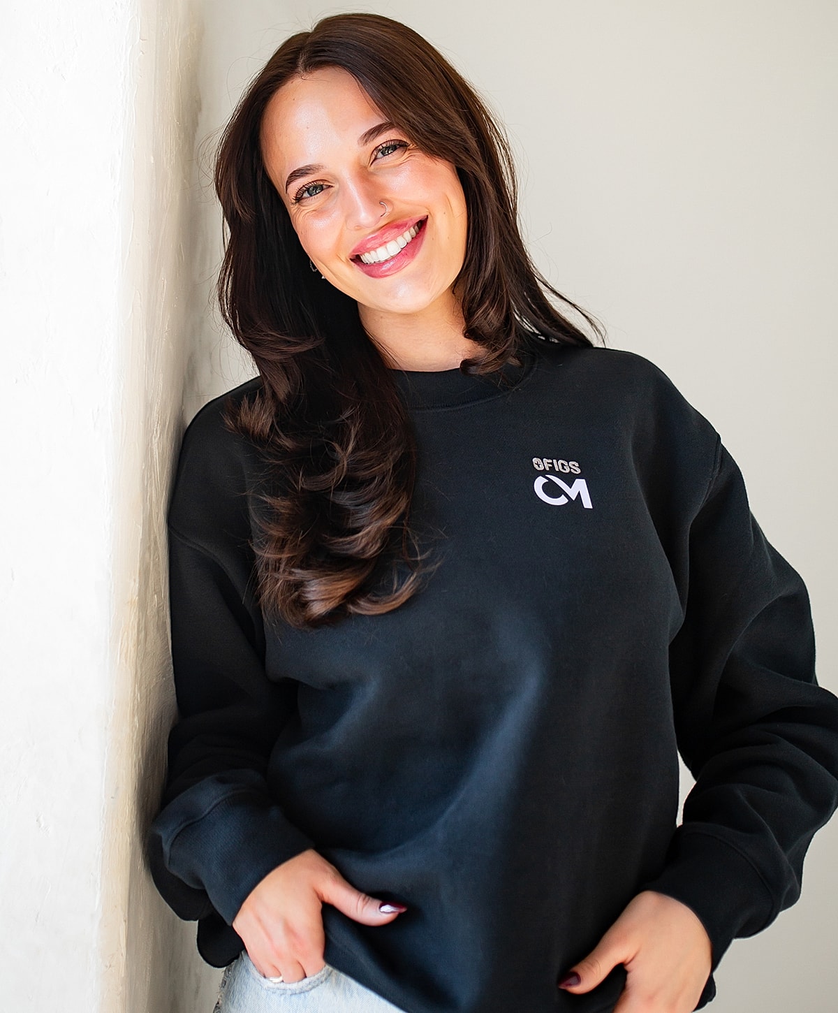 Smiling woman in black sweatshirt, hands on hips.
