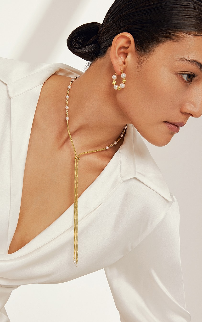 Woman wearing elegant jewelry with white blouse.