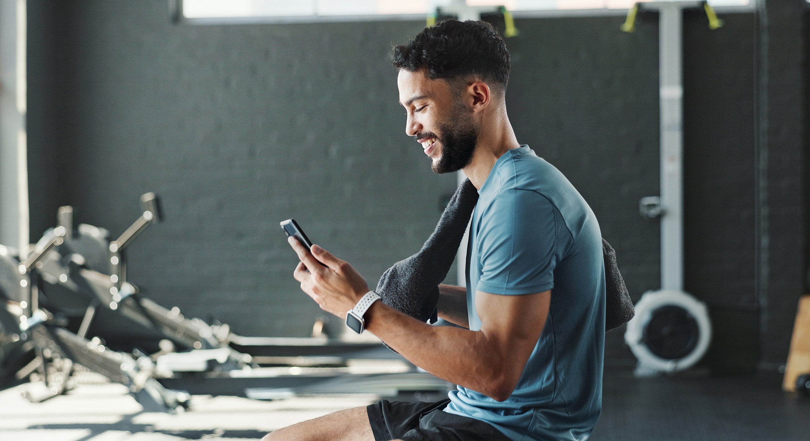 Man in gym checking phone while resting.